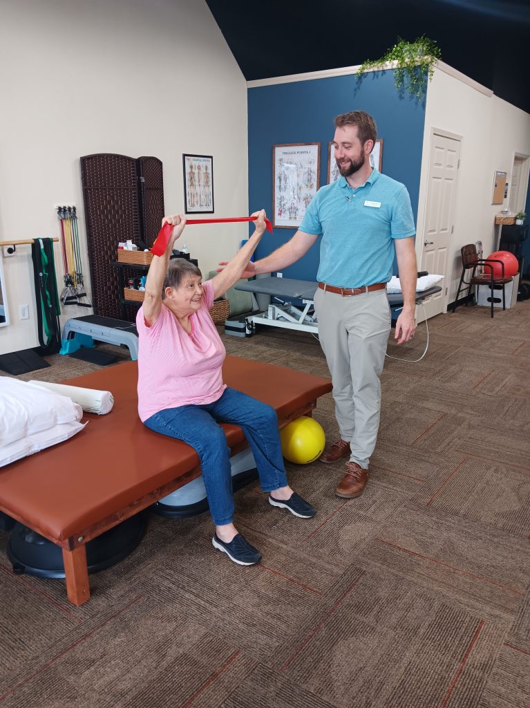 Jason Salisbury PT, DPT showing patient shoulder exercise to help neck and shoulder pain and be able to reach overhead.